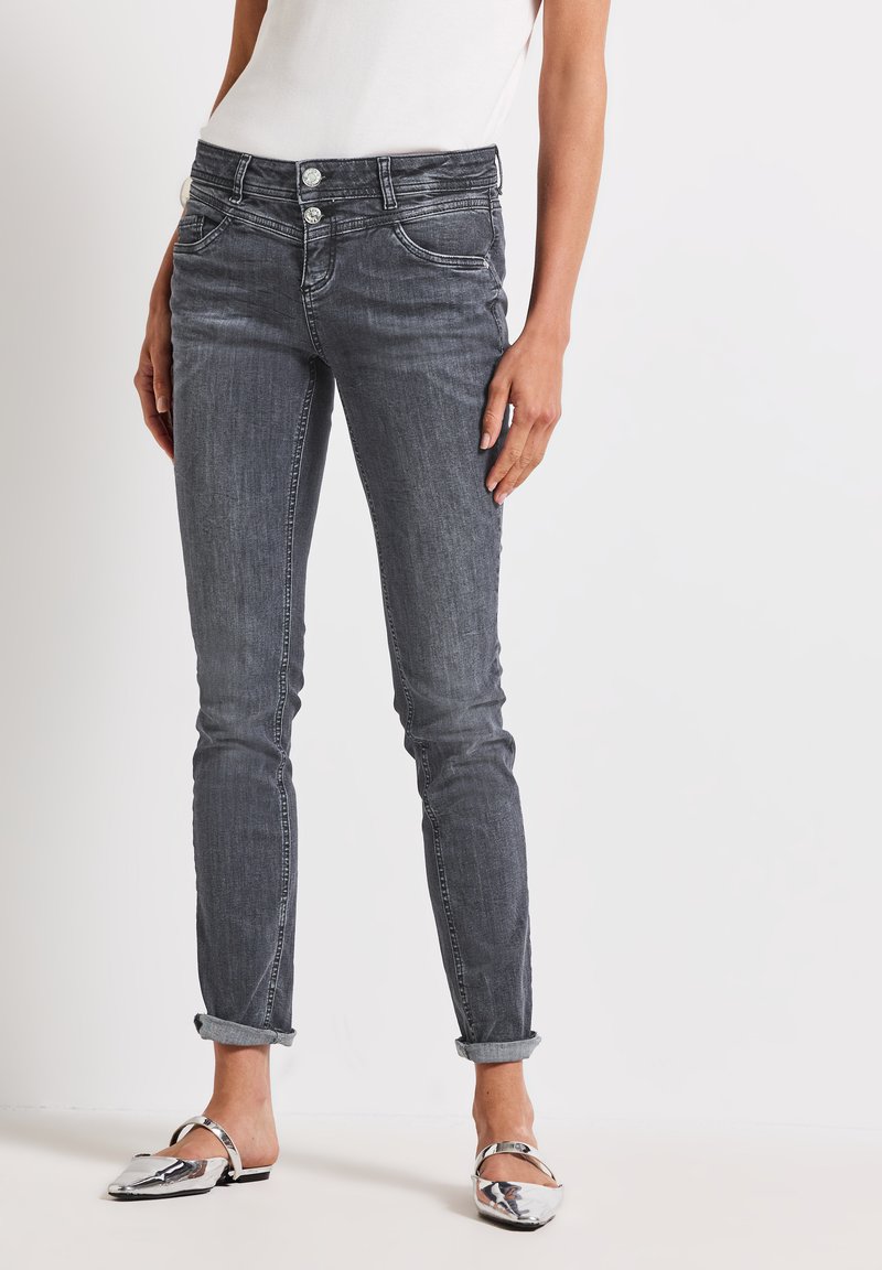 Jeans en denim gris avec une coupe slim, un design à cinq poches, deux boutons à l'avant et des ourlets roulés. Texture lisse avec des détails de décoloration subtile.