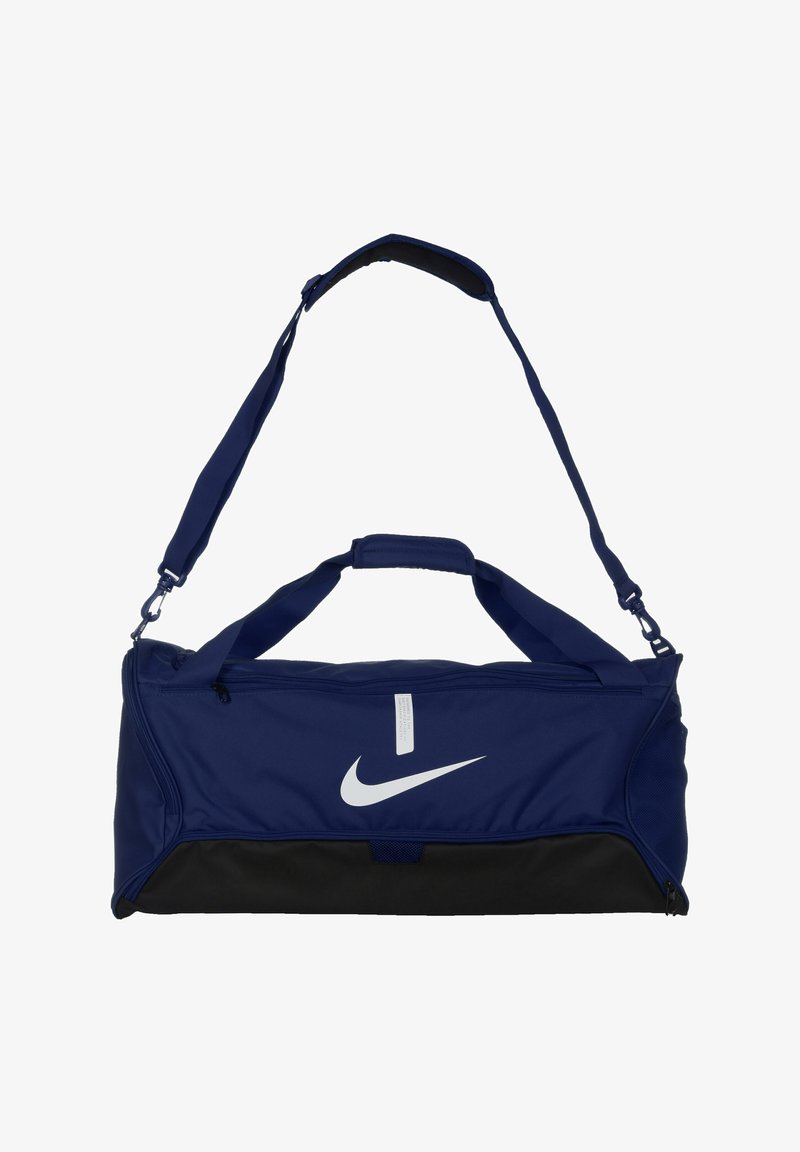 Meripura navy biru yang terbuat dari kain yang tahan lama, dengan logo Nike putih, bagian bawah hitam, dua gagang, dan tali bahu yang dapat disesuaikan.