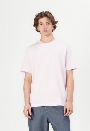 Lyserød bomulds t-shirt med rund hals og korte ærmer. Har et ovalt "adidas" logo i hvid og gul på fronten.