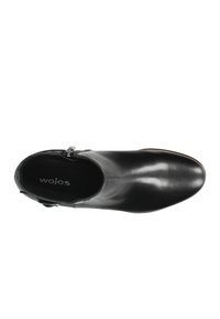Stivale alla caviglia in pelle nera con texture liscia, punta arrotondata, zip laterale e soletta con marchio, caratterizzato da un design elegante e slanciato.