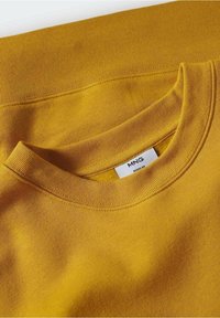 Gelbes Sweatshirt mit geripptem Rundhalsausschnitt und glatter Textur. Auf der Innenseite hinten befindet sich ein Etikett mit "MNG".