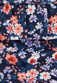 Ziedu audums ar tumši zilu fona, kurā attēloti dažādi ziedi rozā, baltā un purpursarkanā krāsā. Ietver krokas un ribotu tekstūru.