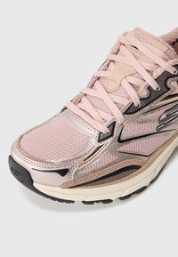 Lichtroze hardloopschoen met een bovenwerk van mesh, metallic accenten en een gestructureerde zool. Bevat dikke veters en een gevoerde inlegzool voor extra ondersteuning.