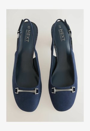 Zapatos slingback de ante azul marino con punta redondeada, acentos de hardware plateado y una correa trasera texturizada para mayor soporte. Forro interior suave.