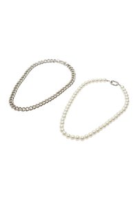 Srebrny naszyjnik łańcuszkowy obok naszyjnika z białymi perłami. Łańcuszek składa się z przeplatanych ogniw, podczas gdy naszyjnik z pereł ma jednorodnie rozmieszczone perły.