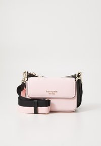 Pink pebbled leather bag with a black side, gold logo, and adjustable strap. Features a flap closure and zipper compartments.