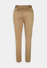 Beige maßgeschneiderte Hosen mit aufgesetzten Gesäßtaschen, Gürtelschlaufen und einer slim fit gerade geschnittenen Beinform, von hinten vor einem weißen Hintergrund präsentiert.