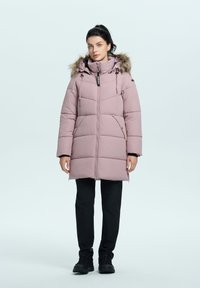Pinker Wintermantel mit Wattierung und Kapuze aus Kunstpelz, mit Reißverschluss vorne und Seitentaschen. Wird über schwarzen Hosen und Stiefeln getragen und bietet eine warme, lässige Passform.