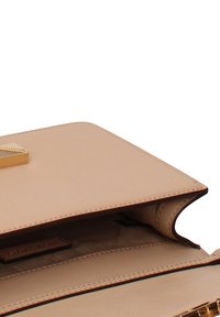 Structured handbag in soft beige leather, featuring a gold hardware clasp, a smooth texture, and an open interior with multiple compartments.