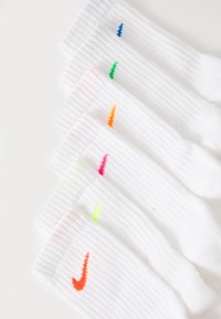 Chaussettes blanches côtelées avec des logos Swoosh colorés en bleu, vert, orange, rose et jaune, disposés dans un ordre dégradé. Texture de tissu douce.