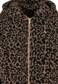 Veste en polaire avec un motif léopard noir et beige, dotée d'une fermeture éclair dorée et d'une capuche. Son tissu texturé et doux améliore la chaleur.
