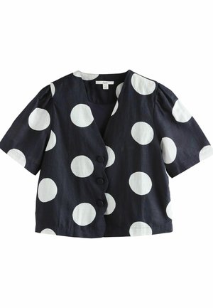 Blusa de manga corta azul marino con grandes lunares blancos, con un escote en V y cinco botones negros en el frente. Textura de tela suave.