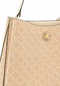 Bolso tote beige con un patrón de monograma, textura suave, un acento de logo circular dorado y dos correas con un borde de color contrastante.