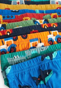 Sept paires de shorts pour enfants exposés, présentant divers motifs colorés, incluant des véhicules et des créatures marines. Fabriqués en tissu doux avec des ceintures élastiques.
