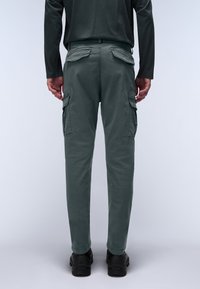 Gray cargo pants with side pockets, a fitted design, and a smooth texture, paired with black shoes. View from the back.