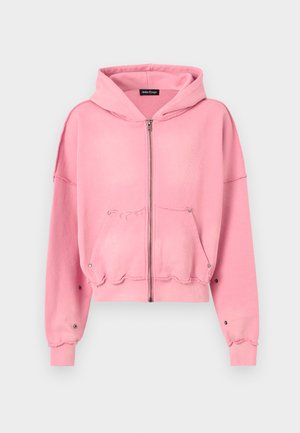 Pink cropped hoodie with a front zipper, drawstring hood, oversized sleeves, and raw hem details. Features two front pockets and snap accents.