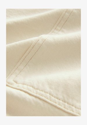 Béžová látka s textúrovanou tkaninou. Viditeľný šev pozdĺž okraja, ktorý vytvára čistý a hladký vzhľad. Ľahká a flexibilná.