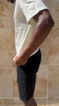 Hvit t-skjorte og svarte denimshorts. T-skjorten har korte ermer, mens shortsene er formsydd med lommer og har en falmet tekstur.