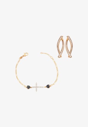 Złota bransoletka z diamentowym krzyżykiem i czarnymi kamieniami w kształcie serca w zestawie ze złotymi kolczykami ozdobionymi diamentami w skręconym wzorze.