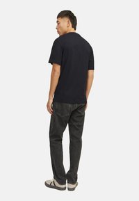 Mørkeblå bomulds t-shirt med korte ærmer og en afslappet pasform, parret med mørkegrå denim jeans og grå sneakers med sorte detaljer.