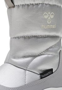 Grå isolerad stövel med en slät satinfinish, gummisula och söm-accenter. Visar "hummel"-logotypen och "hummelTEX"-etiketten.