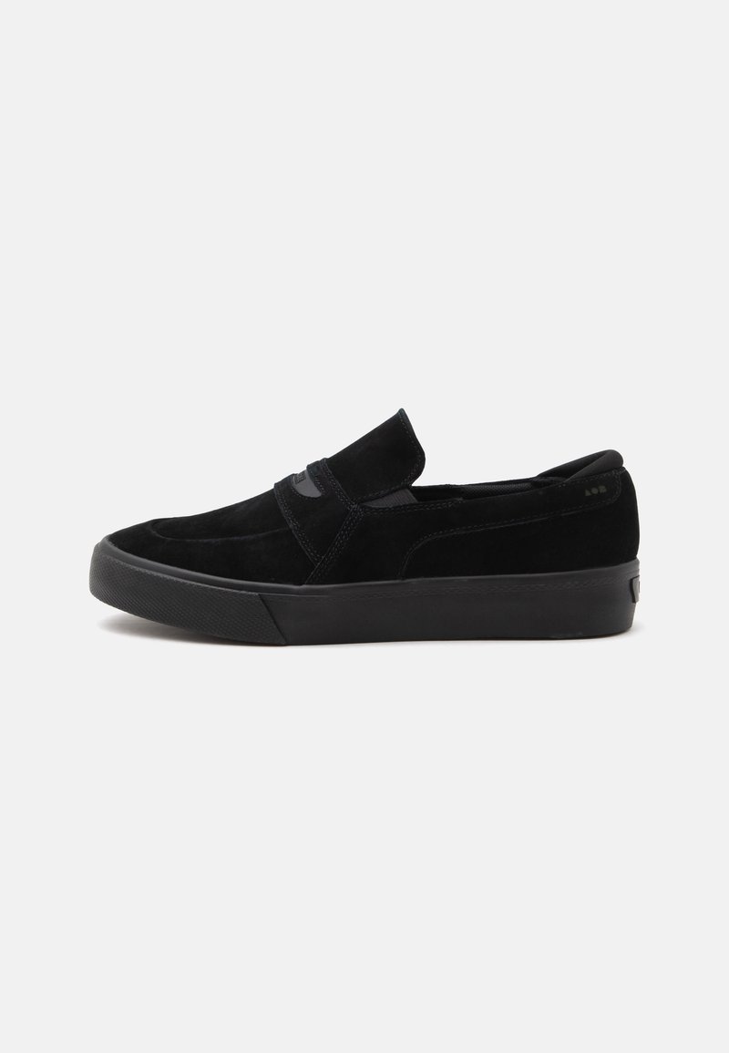 Baskets slip-on en daim noir avec semelle épaisse et panneaux latéraux élastiques, vues de profil sur fond blanc uni.