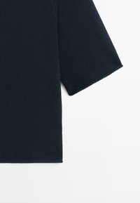 Dunkelblauer, gestrickter Pulloverärmel mit Rippenstruktur vor weißem Hintergrund.