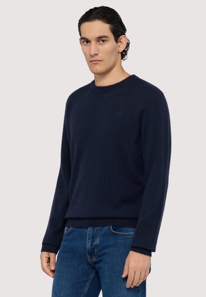 Mørkeblå strikket sweater med rund halsudskæring, lange ærmer og ribbede manchetter. Struktureret stof med en diskret logodetalje på brystet.