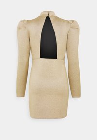 Třpytivé zlaté mini šaty s dlouhým rukávem, vycpanými rameny, vysokým límcem a velkým diamantovým výstřihem na zádech.