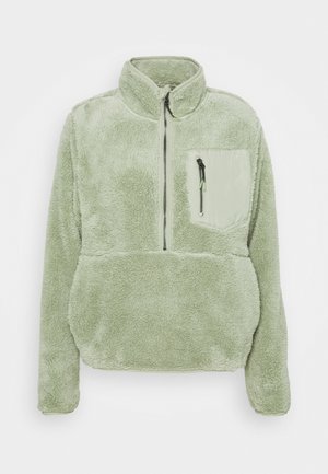 Jasnozielony polarowy sweter z wysokim kołnierzem, frontowym półzamkiem oraz zamykaną na zamek kieszenią na piersi z nylonowym detalem.