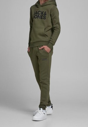 Sudadera verde oliva con gran logo "JACK&JONES", bolsillo frontal, pantalones a juego y zapatillas blancas con acentos negros. Material suave, ajuste casual.