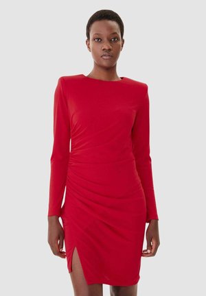 Vestito rosso a maniche lunghe con una silhouette aderente, texture arricciata e uno spacco alto sulla coscia da un lato. Tessuto morbido ed elastico con scollatura tonda.