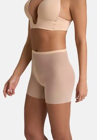 Shorts modellanti a vita alta beige, realizzati in un tessuto liscio e elasticizzato con un design senza cuciture e una vita sottile. Adatti fino a metà coscia.