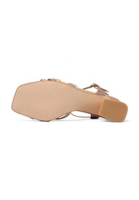 Sandal in beige con cinturini, dotato di un tacco basso a zeppa testurizzato e di una suola liscia. Presenta una fascia larga sulla punta e una fibbia alla caviglia regolabile.