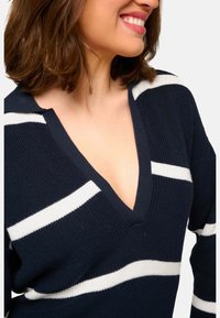 Marineblauer Strickpullover mit weißen Streifen, V-Ausschnitt-Design, mit geripptem Muster und kurzen Ärmeln.