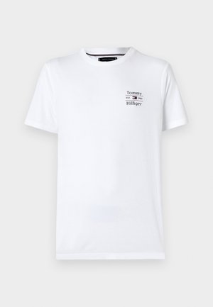 T-shirt bianco a maniche corte in cotone. Presenta una piccola grafica con testo blu e rosso sul lato sinistro del petto che recita "Tommy Hilfiger."