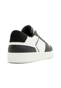 Black and white sneaker featuring textured leather, smooth accents, white sole, and subtle logo detail, with a low-top design.