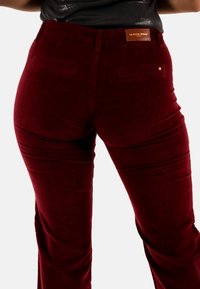 Pantaloni in corduroy bordeaux con vita alta, design a gamba dritta, tasche posteriori e un piccolo dettaglio a stella sul retro, con etichetta in pelle.
