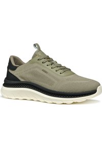 Zapato atlético ligero en verde olivo claro con parte superior de malla transpirable, contrafuerte negro y suela acolchada blanca.