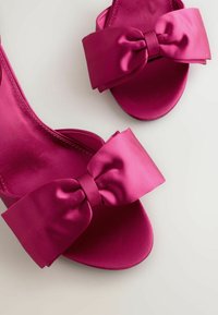 Sandali in satin fucsia con un ampio dettaglio a fiocco sulla cinghia. Design elegante con punta aperta e finitura liscia e lucida.