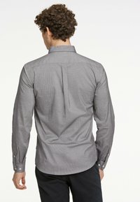Camicia grigia a maniche lunghe con una texture sottile, colletto con bottoni e dettaglio in yoke sul retro. Presenta polsini con bottoni bianchi.