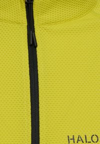Żółta kurtka z zamkiem błyskawicznym, wykonana z teksturowanej siateczki, z czarnym zamkiem biegnącym wzdłuż przodu oraz małym logo na hemie.