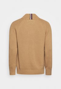 Pullover beige lavorato a maglia con una texture a coste, caratterizzato da un colletto a scialle e una fascia a righe in contrasto nella parte posteriore del collo.