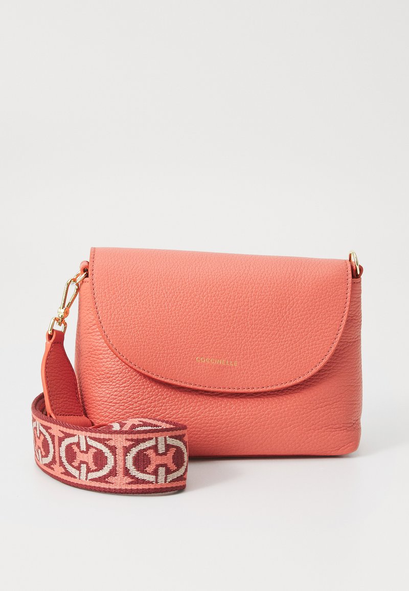 Bolsa de pele coral com um design estruturado, fecho de aba magnético e uma alça decorativa padrão em rosa e creme. Acessórios em dourado.