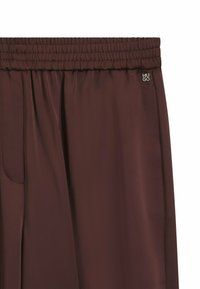 Bruine stretchbroek met subtiele verticale naden en klein metallic HUGO-logo aan de bovenste rechterzijde.