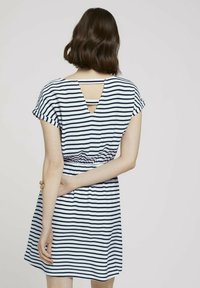 Pruhované šaty v bílé a námořnické modři, krátké rukávy, zúžený pas, výřez ve tvaru V na zádech, měkká tkanina, délka nad kolena.