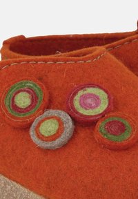 Chaussure en feutre orange avec des appliqués circulaires décoratifs en vert, rouge et violet. Détail cousu le long du bord supérieur, texture douce.