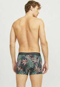 Boxershorts gemaakt van rekbaar materiaal met een zwarte tailleband met de tekst "JACK & JONES." Tropische bladeren en bloempatronen in groen, rood en witte kleuren.