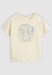 Lys beige bomullst-skjorte med et grafisk design i blått med vinger, stjerner og teksten "LEVI'S 1873" på forsiden. Korte ermer, rund hals.