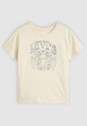 T-shirt en coton beige clair avec un design graphique bleu comportant des ailes, des étoiles et le texte "LEVI'S 1873" sur le devant. Manches courtes, col rond.